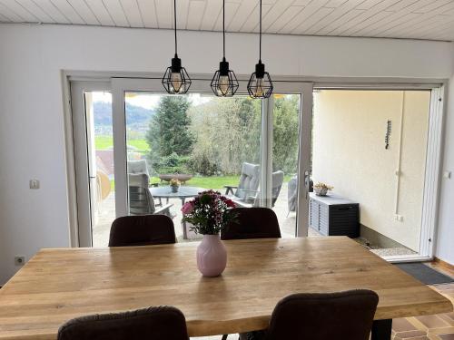 a dining room table with a vase of flowers on it at Terrasse mit Ausblick in Biedenkopf