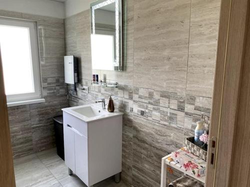 Un baño con un lavabo blanco y un espejo. en House sunlight, en Vranino