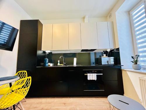 uma cozinha com armários a preto e branco e cadeiras amarelas em Apartment Targowa L8 em Lublin