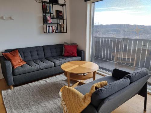 a living room with a couch and a table and a window at Lommedalen Panorama 55m2 in Bærums Verk