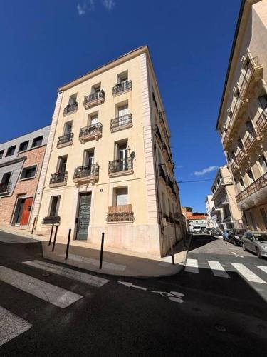 un grand bâtiment blanc au coin d'une rue dans l'établissement Le singulier, à Sète