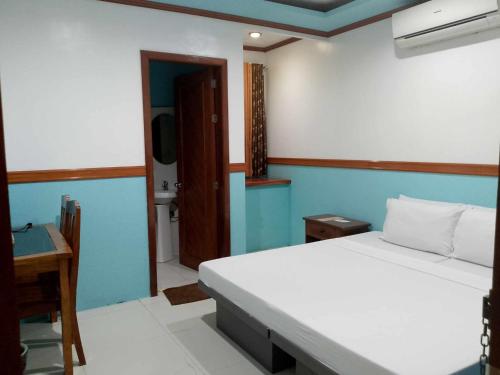 a bedroom with a bed and a desk and a bathroom at SG Hotel in El Nido