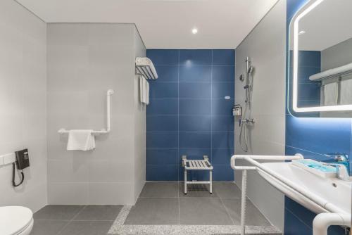 uma casa de banho com azulejos azuis, um WC e um lavatório. em Holiday Inn Express Changchun Ecological Square, an IHG Hotel em Changchun