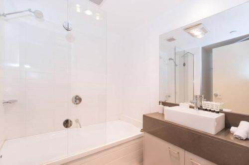 a bathroom with a tub and a sink and a mirror at Harp Haven - Contemporary in Suburban Tree lined Kew in Melbourne