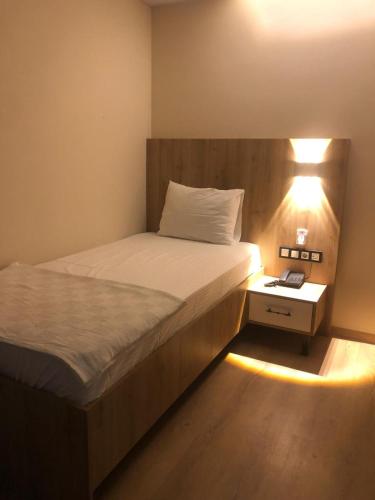 a bedroom with a bed and a night stand with a lamp at Vizyon Otel Darıca in Darıca
