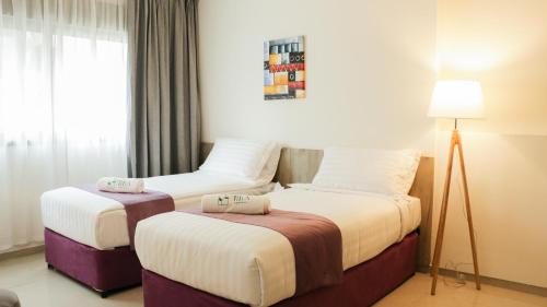 a hotel room with two beds and a lamp at Tilia Hotel Beirut in Beirut