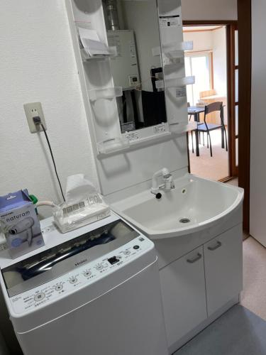 a white kitchen with a stove and a sink at 松ノ木ハウス in Nobeji