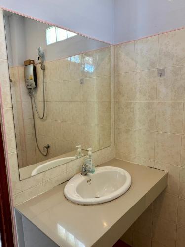 ein Bad mit einem Waschbecken und einer Dusche mit einem Spiegel in der Unterkunft Blue sea house in Ko Phangan