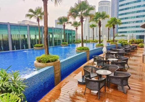 uma piscina de hotel com mesas e cadeiras e palmeiras em Vortex Suites KLCC By MA Tajri em Kuala Lumpur