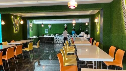 Hotel Destiny في باتنا: مطعم بجدران خضراء وطاولات وكراسي صفراء