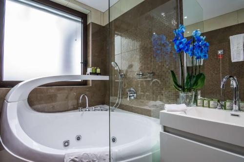 Best Western Plus Olives City Hotel - Free Parking في صوفيا: حمام مع حوض ومغسلة وزهور زرقاء