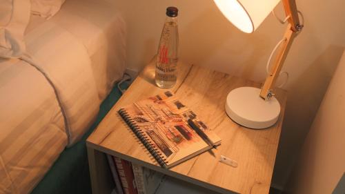 a nightstand with a bed and a lamp and a book at Tilia Hotel Beirut in Beirut