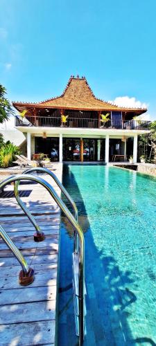 a swimming pool with a building in the background at JOGLO APONG Beachfront Apartment in Tegallengah