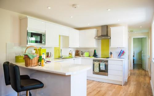 a kitchen with white cabinets and a black chair at The Retreat, own hot tub, romantic escape, near Lyme Regis in Lyme Regis