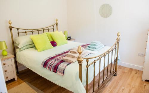 ein Schlafzimmer mit einem Bett mit grünen und gelben Kissen in der Unterkunft The Retreat, own hot tub, romantic escape, near Lyme Regis in Lyme Regis