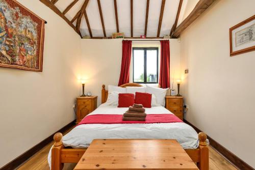 a bedroom with a large bed with red pillows at Flint Barn in Faversham