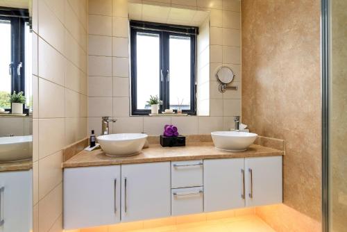 a bathroom with two sinks and a mirror at Finest Retreats - Flint Barn in Faversham