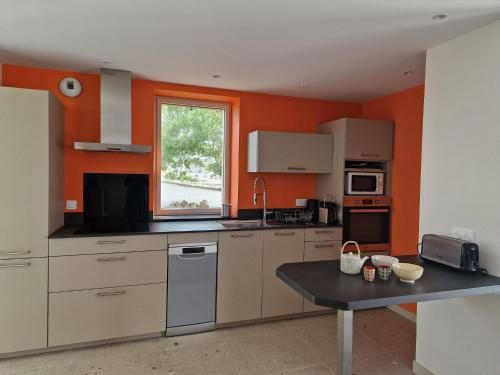 - une cuisine avec des murs orange et une table dans l'établissement Holiday Home in Plougasnou with Sea Views, à Plougasnou
