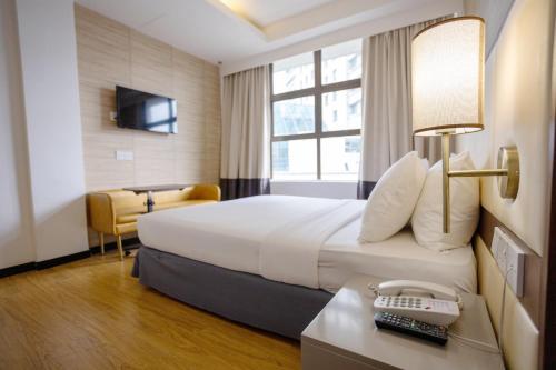 a hotel room with a bed and a desk with a phone at Citrus Hotel Johor Bahru by Compass Hospitality in Johor Bahru