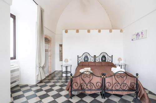 a bed in a bedroom with a checkered floor at Masseria Donna Coletta by Wonderful Italy in Noci