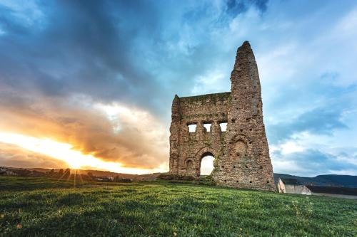 an old stone tower on a hill with a sunset at Contact Hôtel de la Gare et son restaurant Côte à Côte in Autun