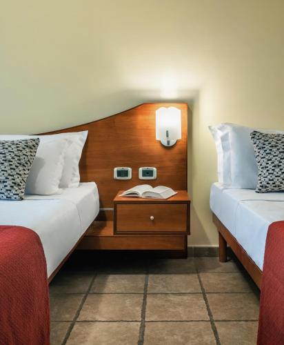 a hotel room with two beds and a night stand at Hotel La Fenice in Castel di Sangro