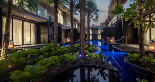 a hotel lobby with palm trees and a pool at Luminous Resort & Spa by Areca in Phuket Town