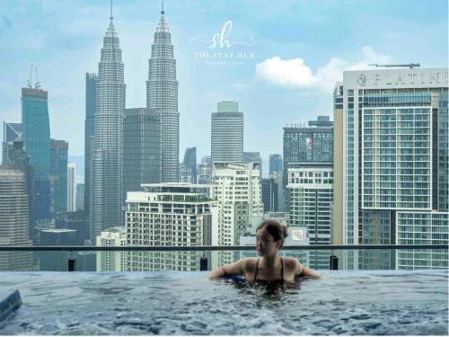 a woman in a hot tub with a view of the city at The Luxe KLCC View Sky Pool in Kuala Lumpur