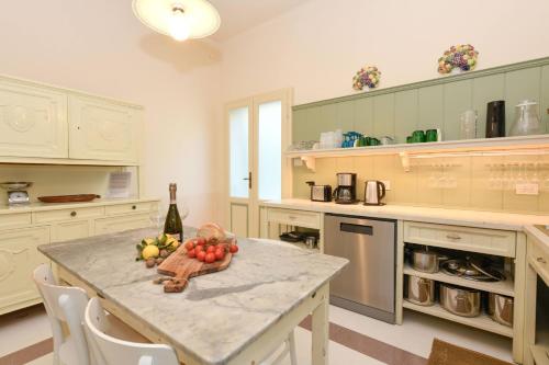 een keuken met een tafel met een fruitschaal en een fles wijn bij Villa Ondina - Wonderful villa with private beach and big garden in Salò