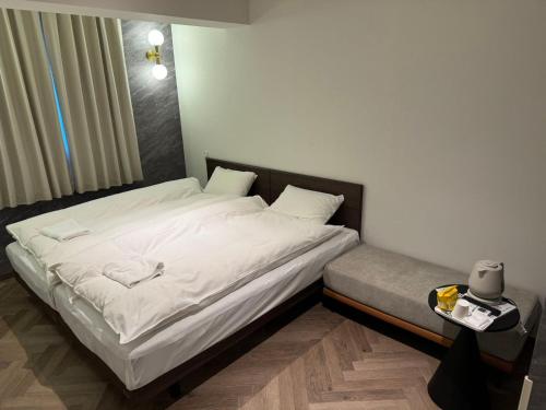 a bed with white sheets and pillows in a bedroom at MARUKOU HOTEL in Tokyo