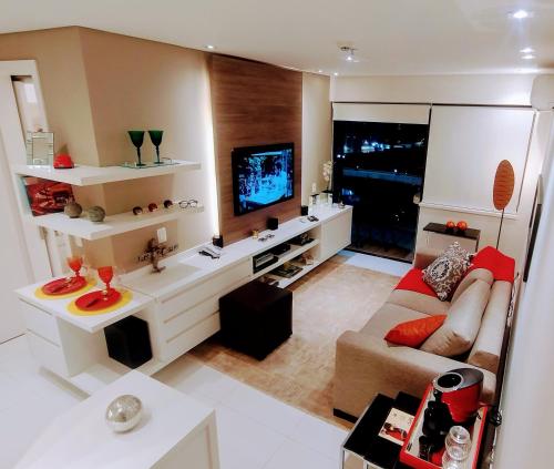 Il comprend un salon doté d'un canapé et d'une télévision à écran plat. dans l'établissement Hotel GRAND M-RCURE - Itaim BiBi- Master Deluxe Veranda Duplex- First Class - Collors Edition- By HouseNN, à São Paulo