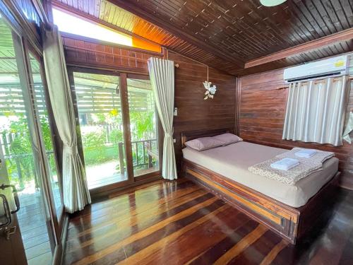 - une chambre avec un lit dans une pièce en bois dans l'établissement Ruen Orathai Resort, à Prachuap Khiri Khan