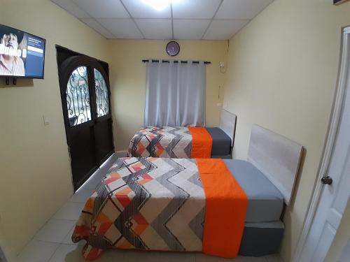 2 Betten in einem Zimmer mit Fenster und Tür in der Unterkunft Hotel Villa Samperio in Poptún
