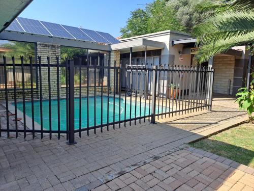 une clôture autour d'une piscine avec des panneaux solaires dans l'établissement Gold Guesthouse and conferences, à Welkom