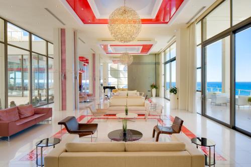 una sala de estar con sofás, mesas y ventanas en Elysium Resort & Spa en Faliraki