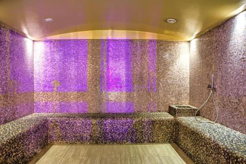 a purple tiled bathroom with a shower with purple lights at Albert Residence Grand Chalet & SPA Poiana Brașov in Poiana Brasov