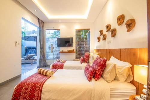 two beds in a hotel room with a tv at Exquisite 4br Haven, 5min Stroll To Beach Canggu in Canggu
