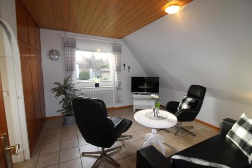 ein Wohnzimmer mit Stühlen, einem Tisch und einem TV in der Unterkunft De grote Linde in Heiligenhafen