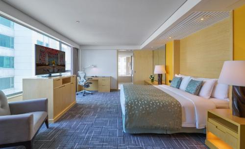 a hotel room with a large bed and a desk at Marco Polo Wuhan in Wuhan