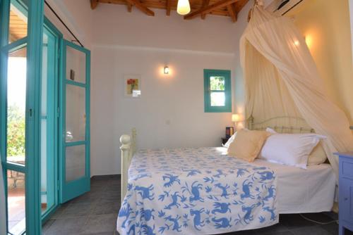 Schlafzimmer mit einem Bett mit einer blauen und weißen Bettdecke in der Unterkunft Icon Painter Villa 'Peroulia 4' in Kómboi