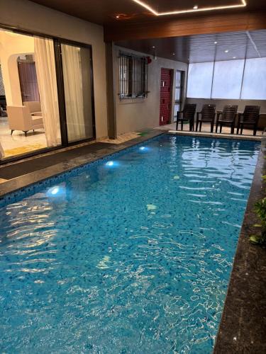 a large swimming pool with blue water in a hotel at ll GOLDEN LEAF ll 3BHK ll AC ll in Lonavala