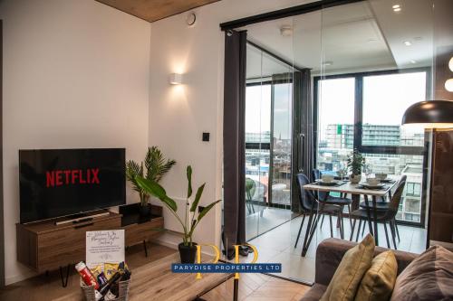 a living room with a tv and a table with chairs at Mancunian Luxury Suite - Stylish & Warm 1-Bed - Ideal For Business or Work Stays - By Parydise Properties in Manchester