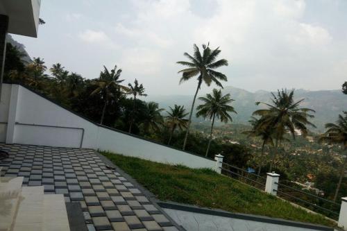 a view of a building with palm trees in the background at OYO Home Homeplus Summer Club 2bhk Peaceful Nature Munnar in Anaviratty