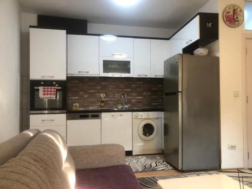 a kitchen with white cabinets and a stainless steel refrigerator at Orion apartment in Pristina