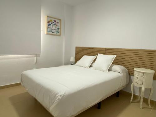 a bedroom with a large white bed with a wooden headboard at City & Beach Top-Floor Apartment in Fuengirola