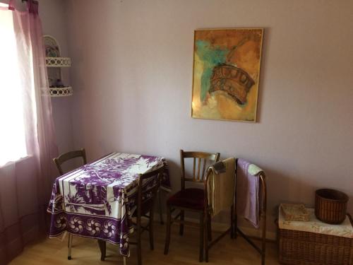einen Tisch und Stühle in einem Zimmer mit Gemälde in der Unterkunft AUBERGE LA ROMAINE in Maizières