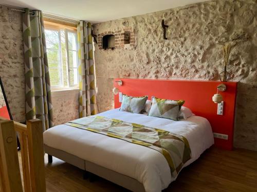 a bedroom with a red headboard and a bed at Le Moulin de Moquesouris - Chambres d'hôtes et table d'hôte in Nazelles