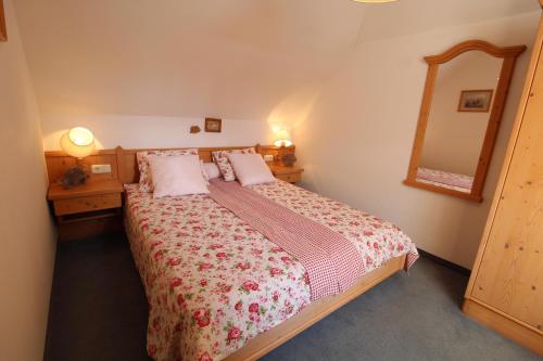 a bedroom with a large bed and a mirror at Landhaus Nockalm in Bad Kleinkirchheim