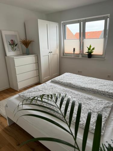 a white bedroom with a bed and two windows at Modern & großzügig! Ideal für Familie & Arbeit in Linden