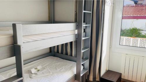 Ce lit superposé se trouve dans un dortoir doté d'une fenêtre. dans l'établissement Bonne Surprise, T3 terrasse pr. plage/ centre/gare, à Arcachon
